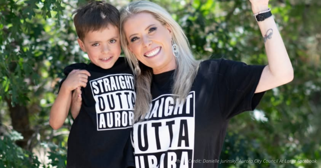 Danielle Jurinsky smiling with her young son wearing matching “Straight Outta Aurora” shirts
