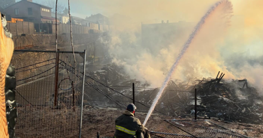 Lone firefighter sprays water on massive apartment fire.
