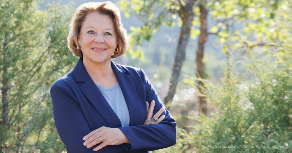 Naomi Riess standing outdoors in Southwest Colorado wearing a navy blazer with arms crossed
