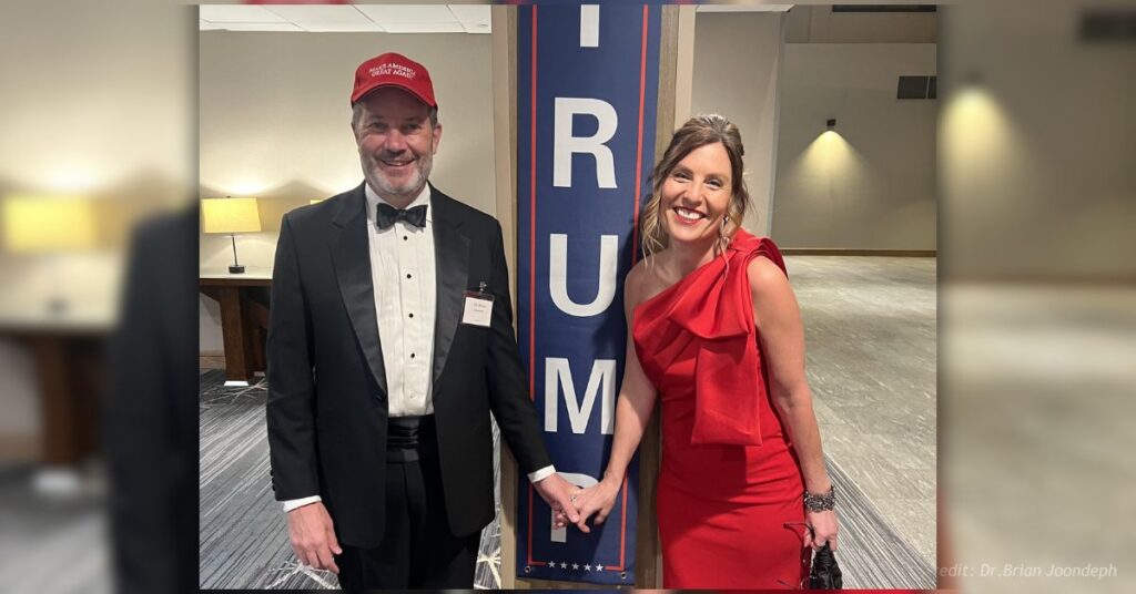 Dr. Brian Joondeph and his wife pose beside a Trump “Save America Again” banner at the Colorado inaugural ball.