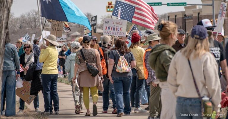 Protesters gather with signs and American flags during a No Kings demonstration in Berthoud, Colorado.