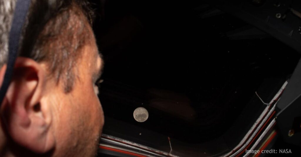 Artemis II commander and NASA astronaut Reid Wiseman looks out one of the Orion spacecraft's main cabin windows at the Moon