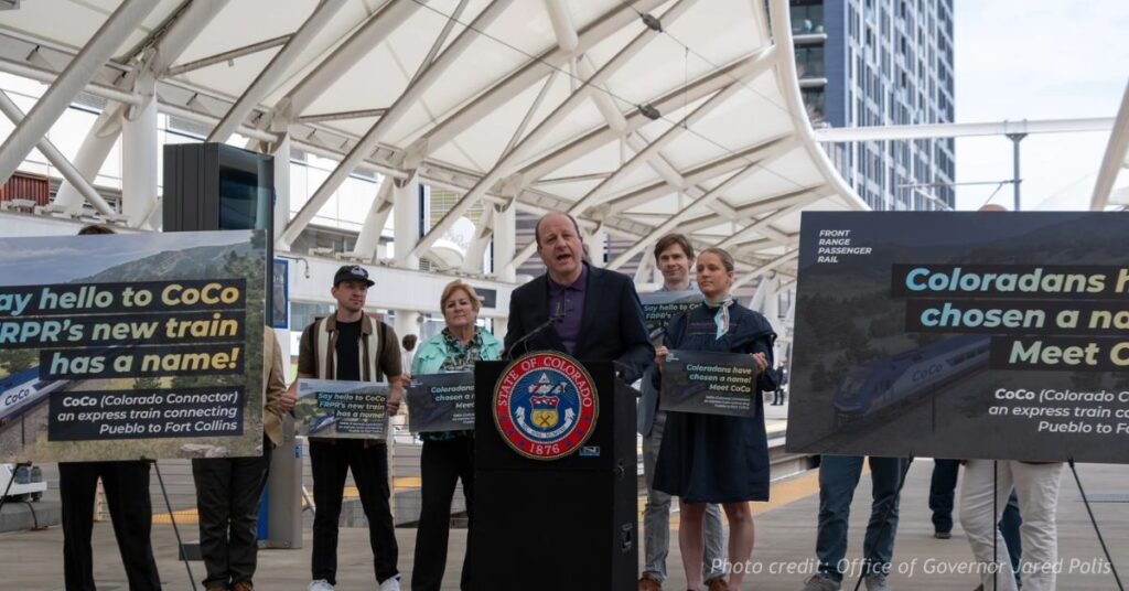 Gov. Jared Polis speaks at a podium at Denver Union Station during the April 6, 2026 ceremony announcing Colorado Connector as the name of the future Front Range passenger rail service.