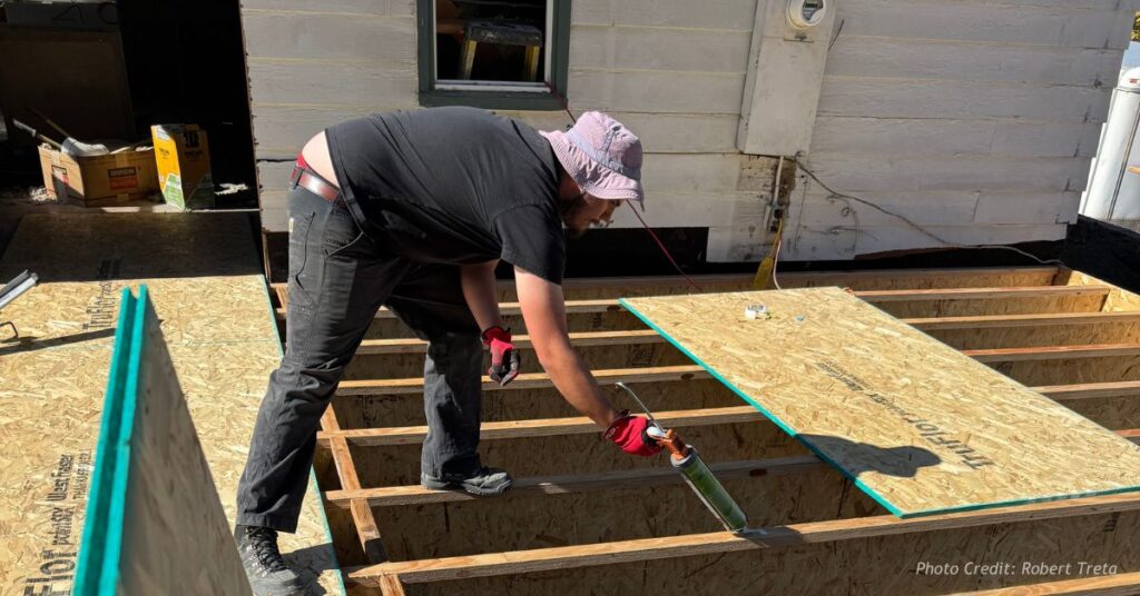 Builder working on exposed floor framing during home remodel in Arvada before regulatory issues escalated